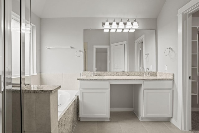 bathroom featuring vanity, a relaxing tiled tub, and tile patterned floors