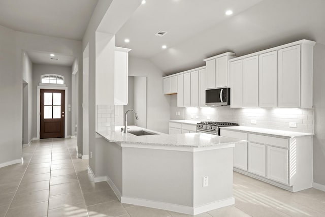 kitchen featuring sink, white cabinetry, light stone counters, appliances with stainless steel finishes, and backsplash