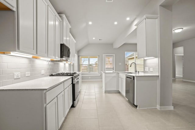 kitchen with white cabinetry, sink, light tile patterned floors, stainless steel appliances, and light stone countertops