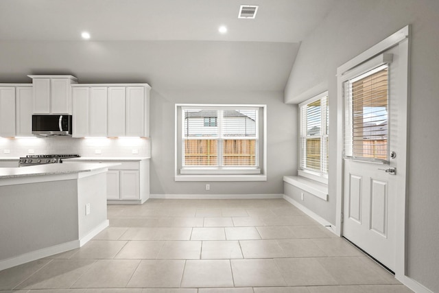 kitchen featuring white cabinetry, stainless steel appliances, vaulted ceiling, and tasteful backsplash