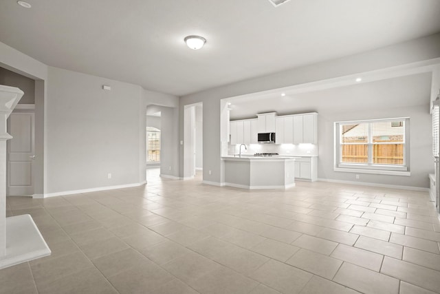 unfurnished living room featuring sink and light tile patterned floors