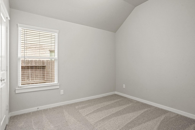 carpeted empty room with lofted ceiling