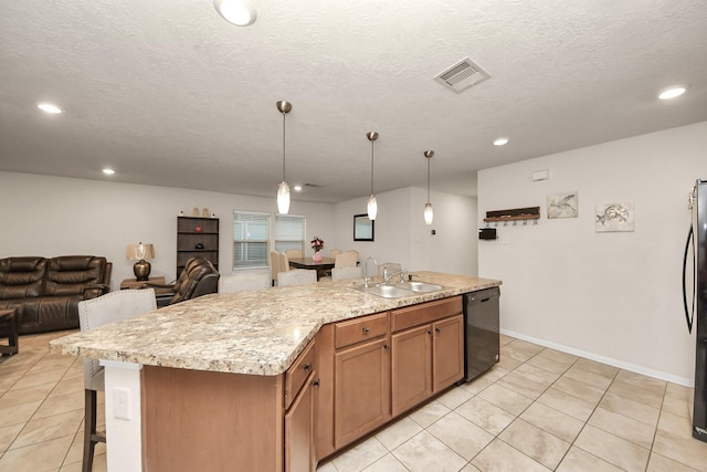 kitchen with sink, hanging light fixtures, a kitchen island with sink, black appliances, and light stone countertops