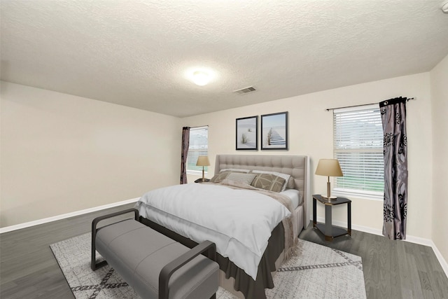 bedroom featuring dark hardwood / wood-style flooring, multiple windows, and a textured ceiling