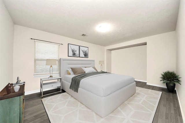 bedroom with dark hardwood / wood-style floors and a textured ceiling