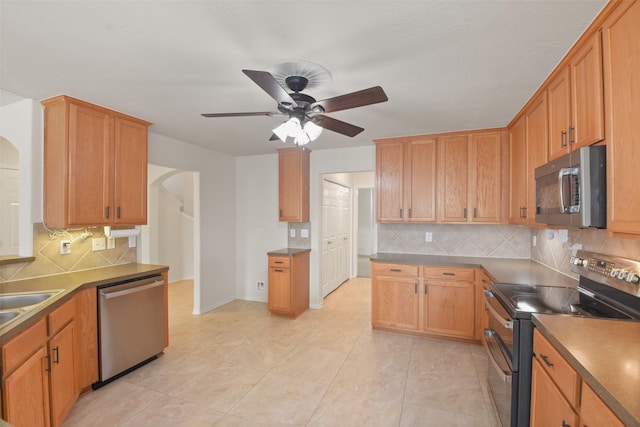 kitchen featuring ceiling fan, stainless steel appliances, light tile patterned floors, and backsplash