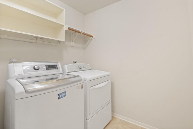 clothes washing area featuring light tile patterned floors and washing machine and clothes dryer