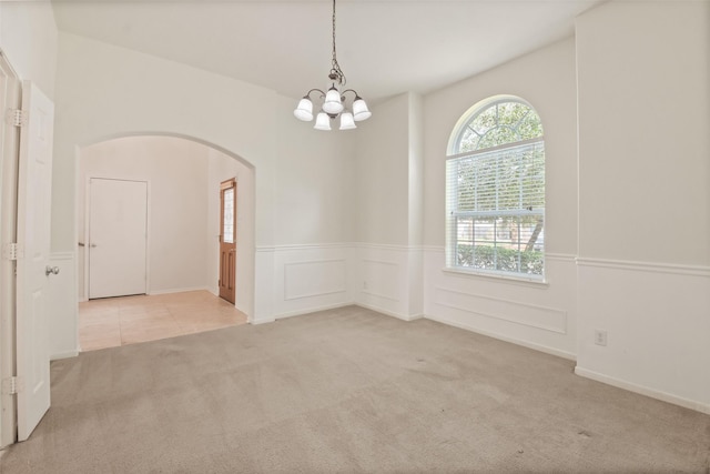 spare room featuring an inviting chandelier and light colored carpet