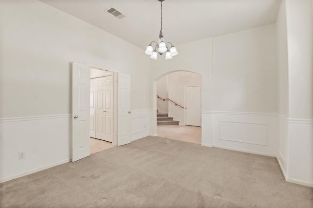 empty room featuring light carpet and a notable chandelier