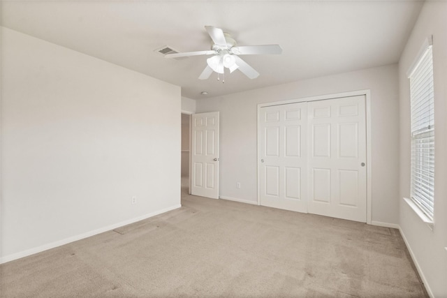 unfurnished bedroom with light carpet, ceiling fan, and a closet