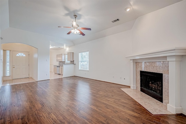 unfurnished living room with light hardwood / wood-style floors, a tile fireplace, and ceiling fan