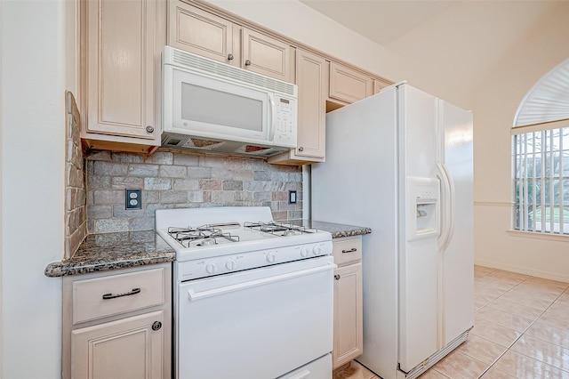 kitchen featuring backsplash, white appliances, dark stone counters, and light tile patterned floors