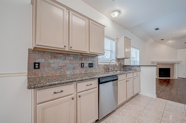 kitchen featuring light tile patterned floors, dishwasher, backsplash, cream cabinetry, and dark stone counters