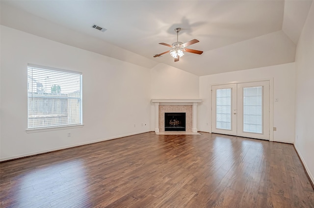 unfurnished living room with french doors, wood-type flooring, vaulted ceiling, a tile fireplace, and ceiling fan