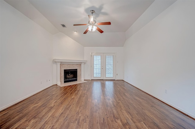 unfurnished living room with lofted ceiling, a tile fireplace, ceiling fan, hardwood / wood-style floors, and french doors