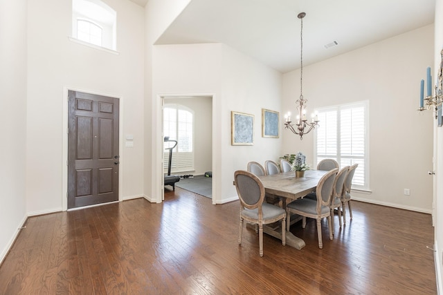 dining area featuring a high ceiling, dark hardwood / wood-style floors, and a notable chandelier