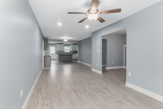 unfurnished living room with light wood-type flooring and ceiling fan