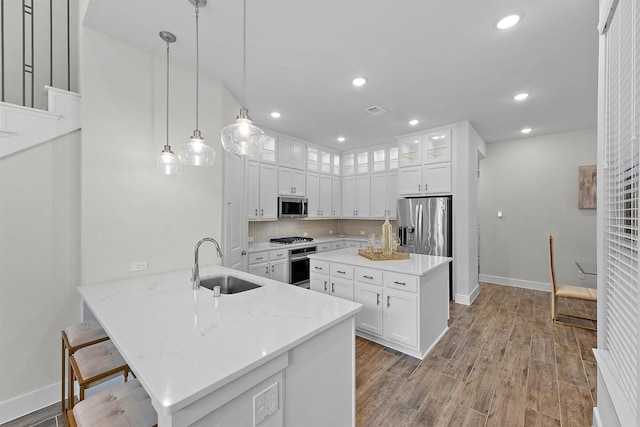 kitchen with decorative light fixtures, sink, white cabinets, light stone counters, and stainless steel appliances