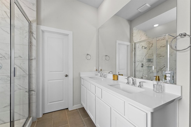 bathroom with a shower with door, vanity, and tile patterned flooring