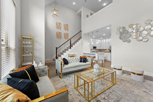 living room featuring a chandelier, light wood-type flooring, and a high ceiling