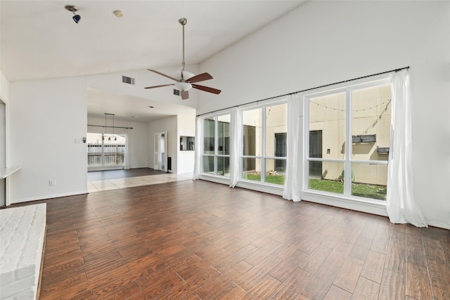 unfurnished living room featuring a healthy amount of sunlight, high vaulted ceiling, dark hardwood / wood-style floors, and ceiling fan