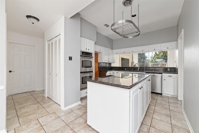 kitchen featuring a kitchen island, appliances with stainless steel finishes, white cabinetry, sink, and light tile patterned floors