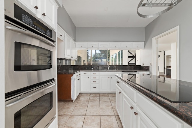 kitchen with white cabinetry, stainless steel double oven, and sink