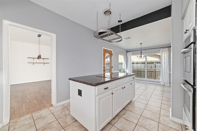 kitchen with white cabinetry, hanging light fixtures, a center island, and dark stone counters