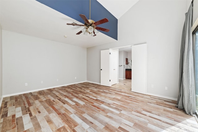 unfurnished bedroom with ensuite bath, high vaulted ceiling, and light hardwood / wood-style floors