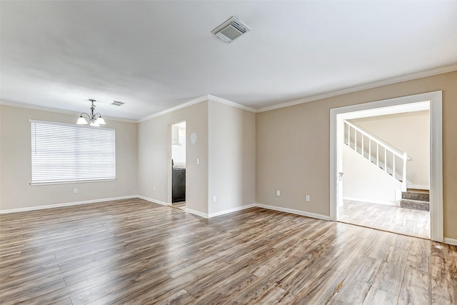 empty room with hardwood / wood-style flooring, ornamental molding, and an inviting chandelier