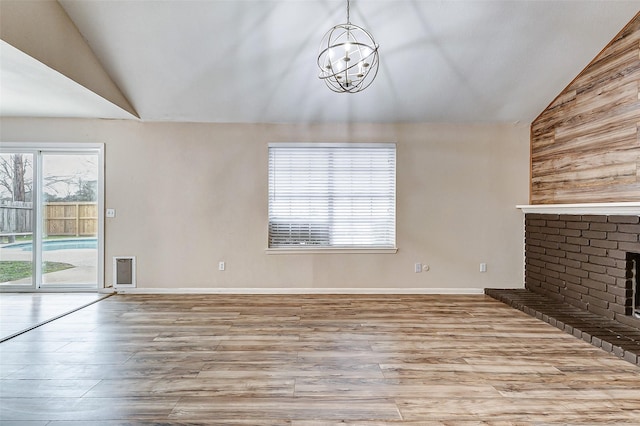 unfurnished living room featuring lofted ceiling, a fireplace, an inviting chandelier, and light wood-type flooring