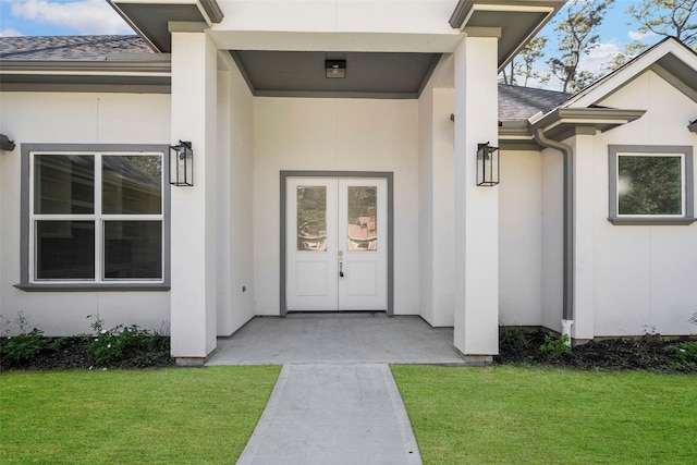 view of exterior entry featuring a yard and french doors