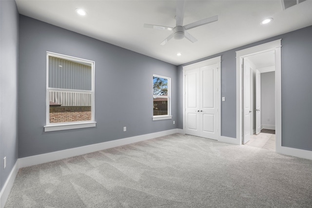 unfurnished bedroom with light colored carpet, ceiling fan, and a closet