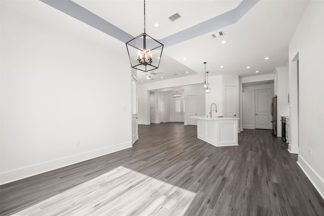 unfurnished living room featuring an inviting chandelier, sink, and dark wood-type flooring