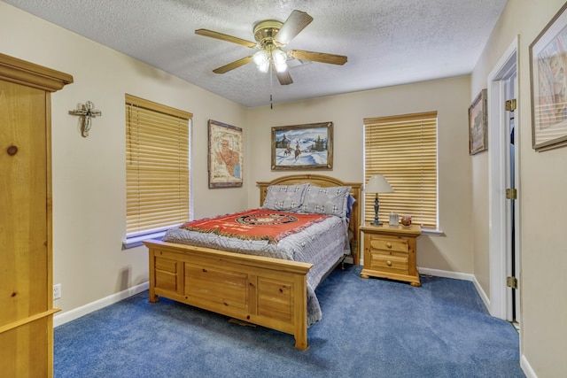 bedroom with ceiling fan, dark carpet, and a textured ceiling