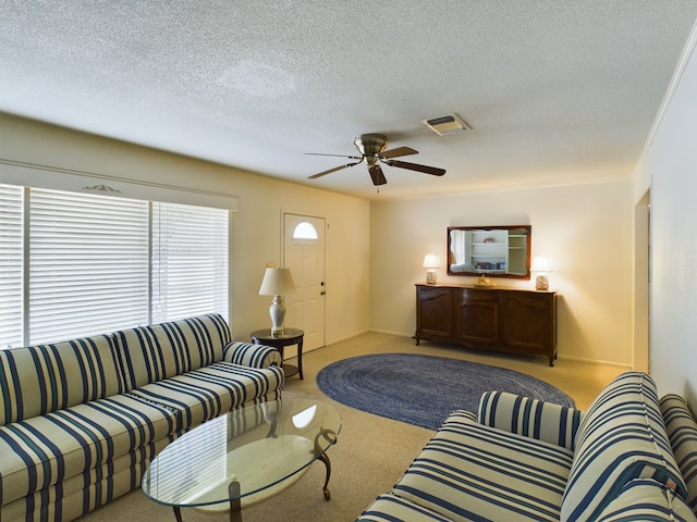 living area featuring a ceiling fan, light colored carpet, visible vents, and a textured ceiling