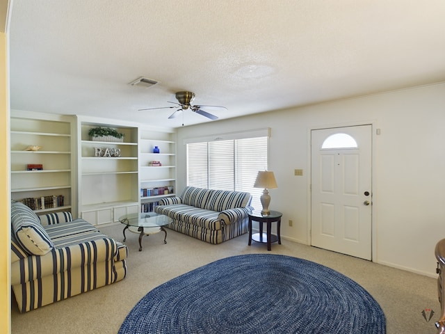 living room with a textured ceiling, ceiling fan, light carpet, visible vents, and baseboards