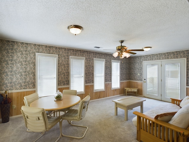 interior space featuring wallpapered walls, a textured ceiling, and wainscoting