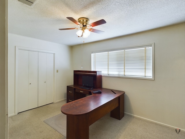 office space featuring light colored carpet, visible vents, ceiling fan, and a textured ceiling