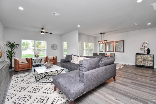 living room featuring plenty of natural light, ceiling fan with notable chandelier, and light wood-type flooring