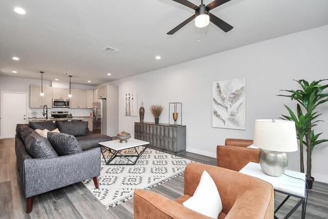 living room featuring wood-type flooring, sink, and ceiling fan