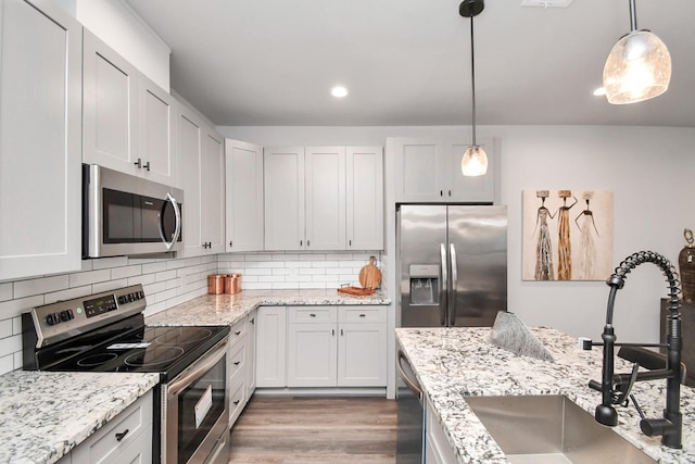 kitchen with pendant lighting, sink, white cabinetry, backsplash, and stainless steel appliances