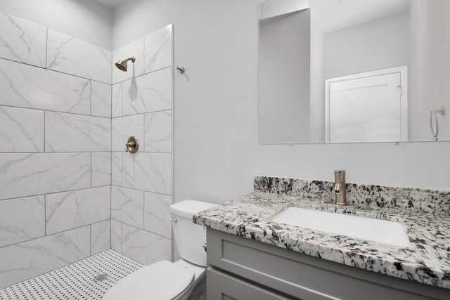 bathroom with vanity, a tile shower, and toilet