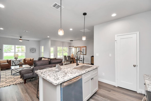 kitchen with sink, hanging light fixtures, white cabinets, a center island with sink, and stainless steel dishwasher