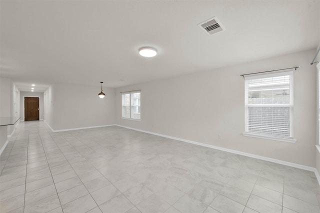 empty room featuring baseboards, visible vents, and light tile patterned flooring