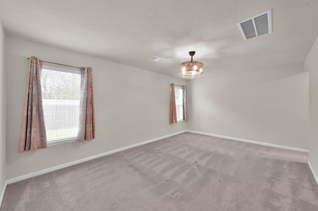 unfurnished room featuring baseboards, visible vents, and light colored carpet