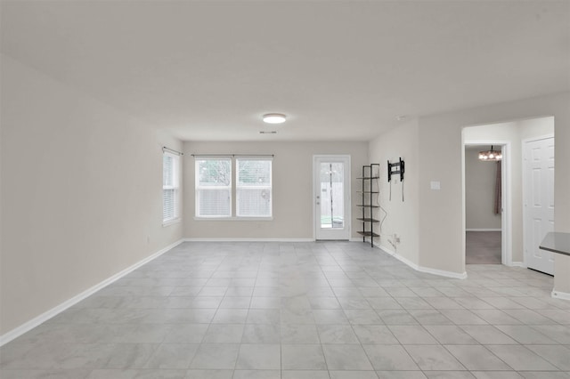 spare room featuring a notable chandelier, light tile patterned floors, visible vents, and baseboards