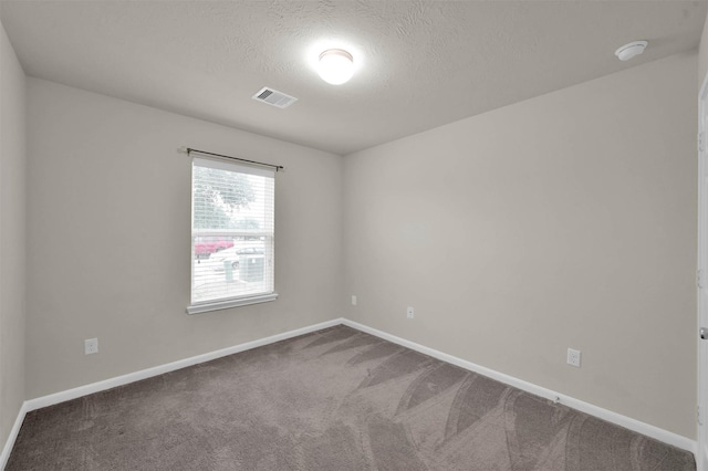 carpeted spare room with visible vents, a textured ceiling, and baseboards