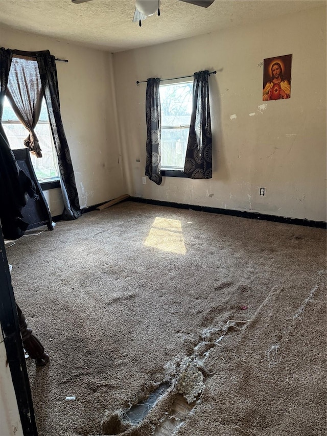 carpeted empty room with ceiling fan and a textured ceiling