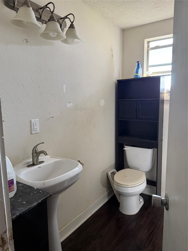 bathroom with hardwood / wood-style flooring, toilet, and a textured ceiling